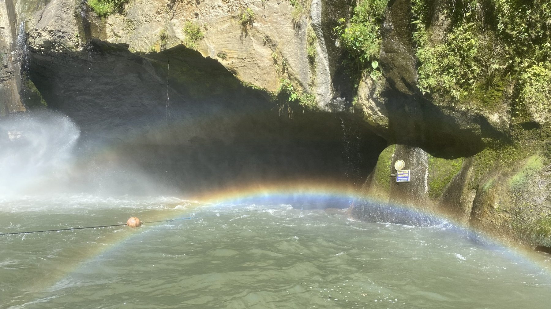 Rainbow across the water beneath a Bali waterfall