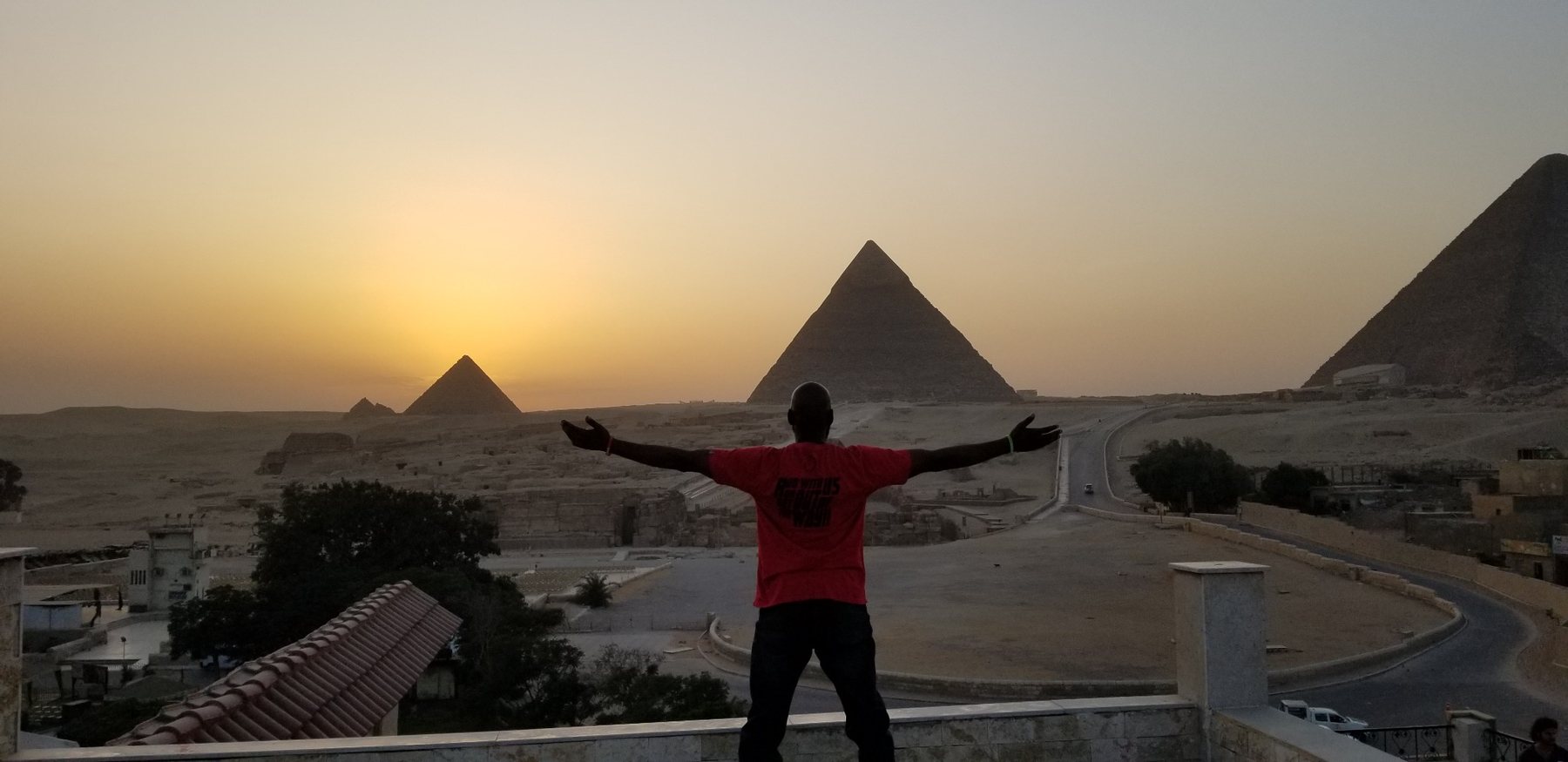 Darnell seated with the pyramids behind him at sunset