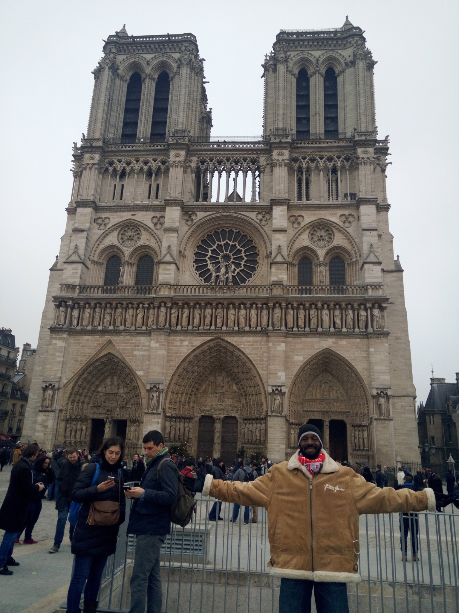 Darnell standing with arms open in front of Notre-Dame Cathedral on an earlier Paris trip